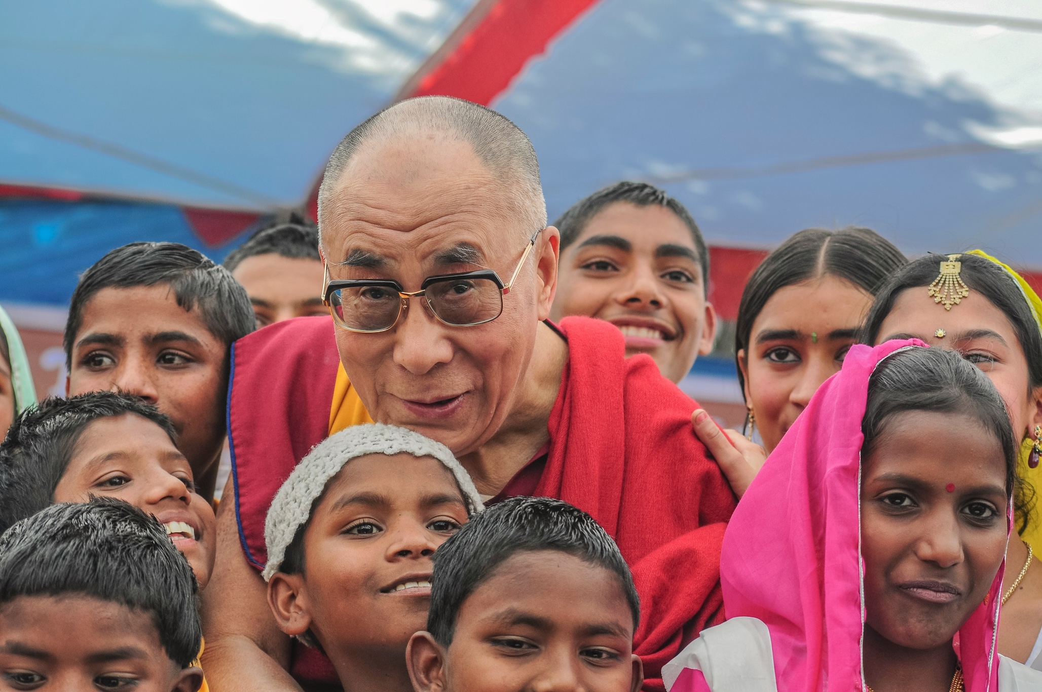 A senior Tibetan Buddhist leader interacting with children during a community gathering