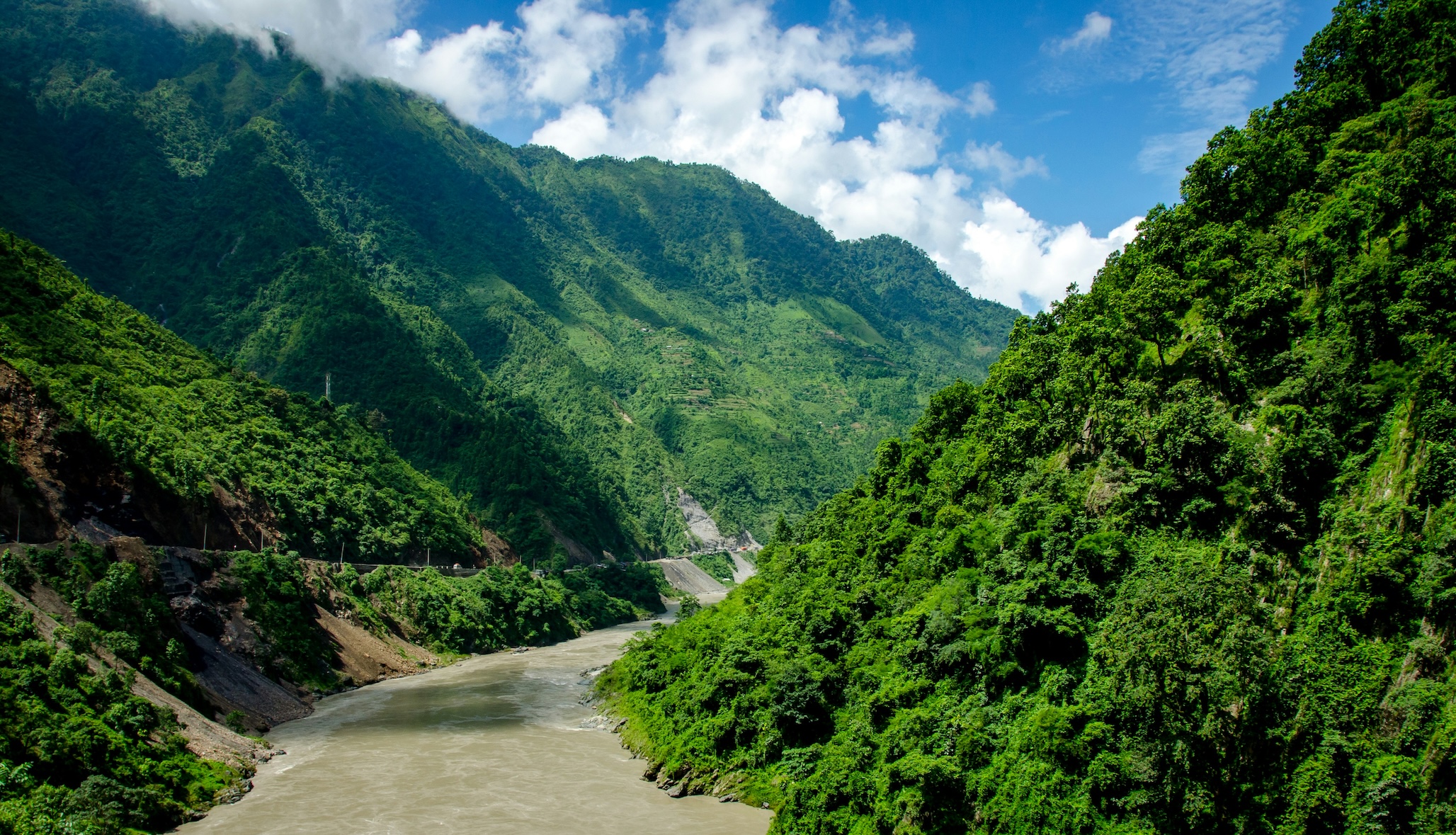 River flowing through lush green hills near Dharamshala during the monsoon season