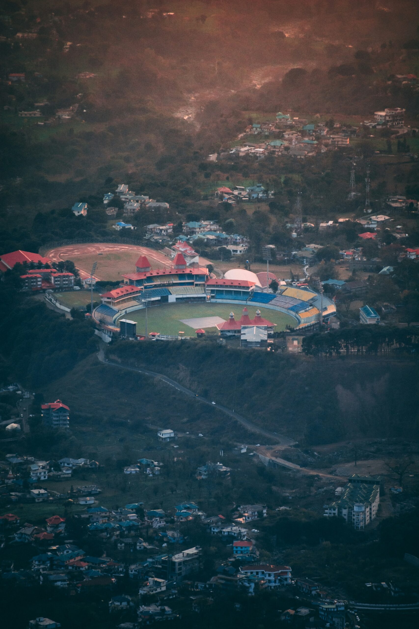 Aerial view of Dharamshala cricket stadium surrounded by hills and residential areas