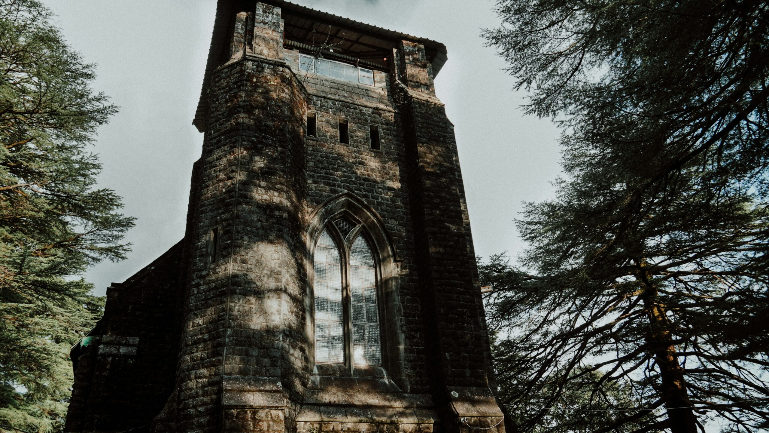 Stone façade of St. John in the Wilderness Church surrounded by cedar trees in Dharamshala