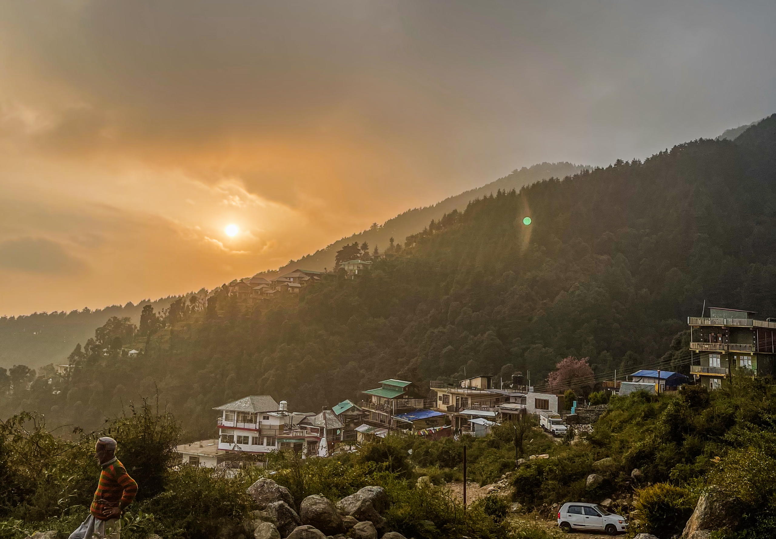 Sunset over hillside homes and forested slopes in Dharamkot