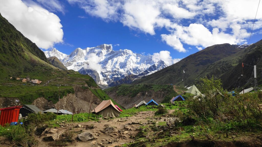 Tents set up in a high-altitude Himalayan campsite with snow-covered peaks in the background