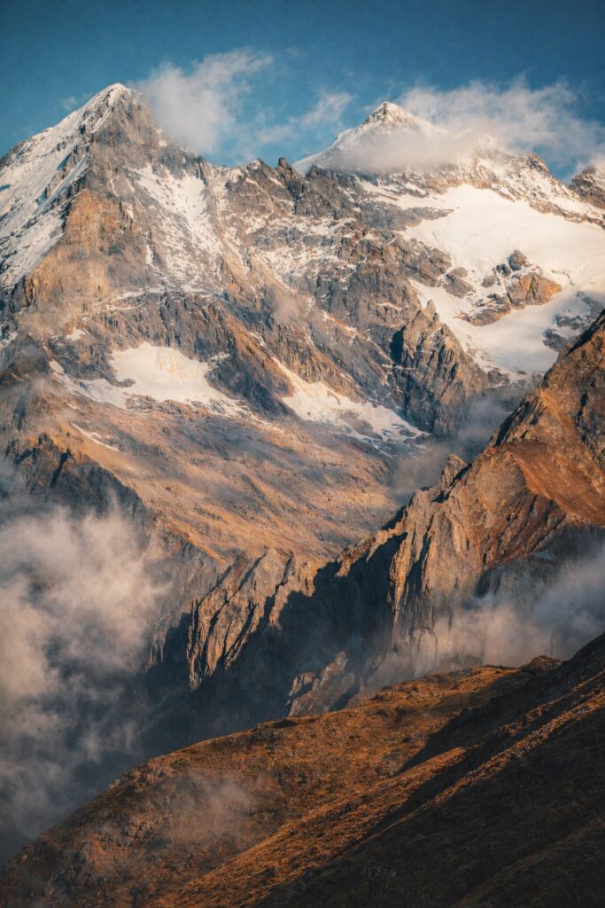 Snow-covered Himalayan peaks rising above rugged high-altitude terrain on a challenging trek in Dharamshala