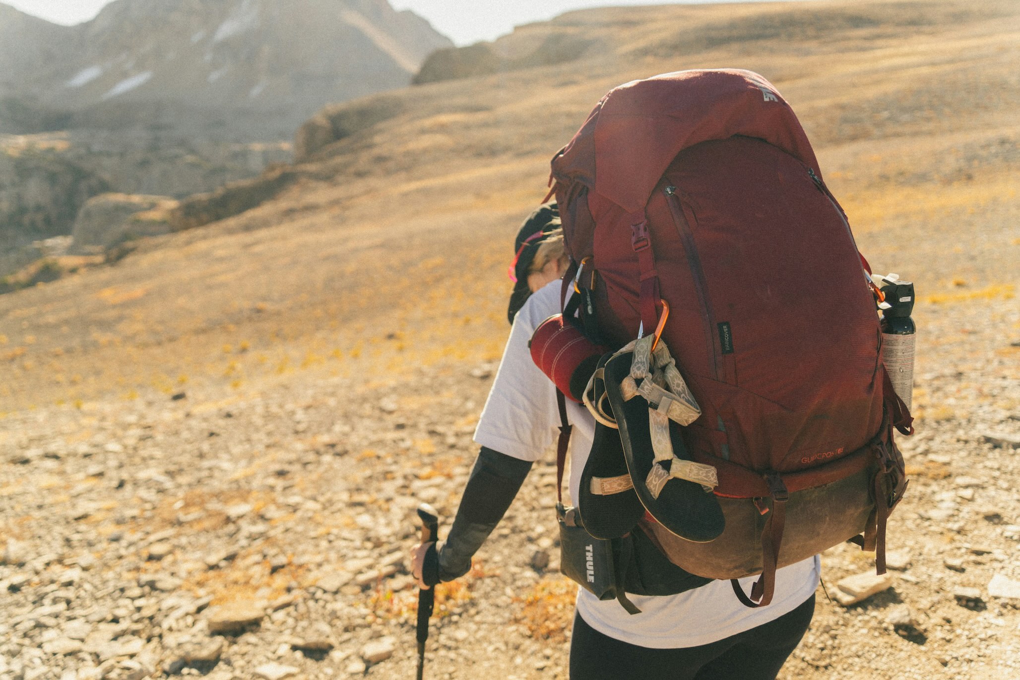 Trekker carrying a large backpack with hiking gear on a rocky high-altitude trail in the Himalayas