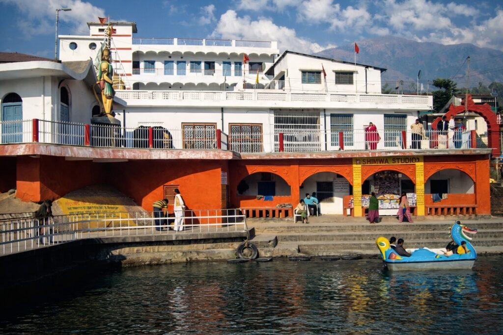 Chamunda Devi Temple in Dharamshala beside river with colorful temple complex and Dhauladhar mountain backdrop