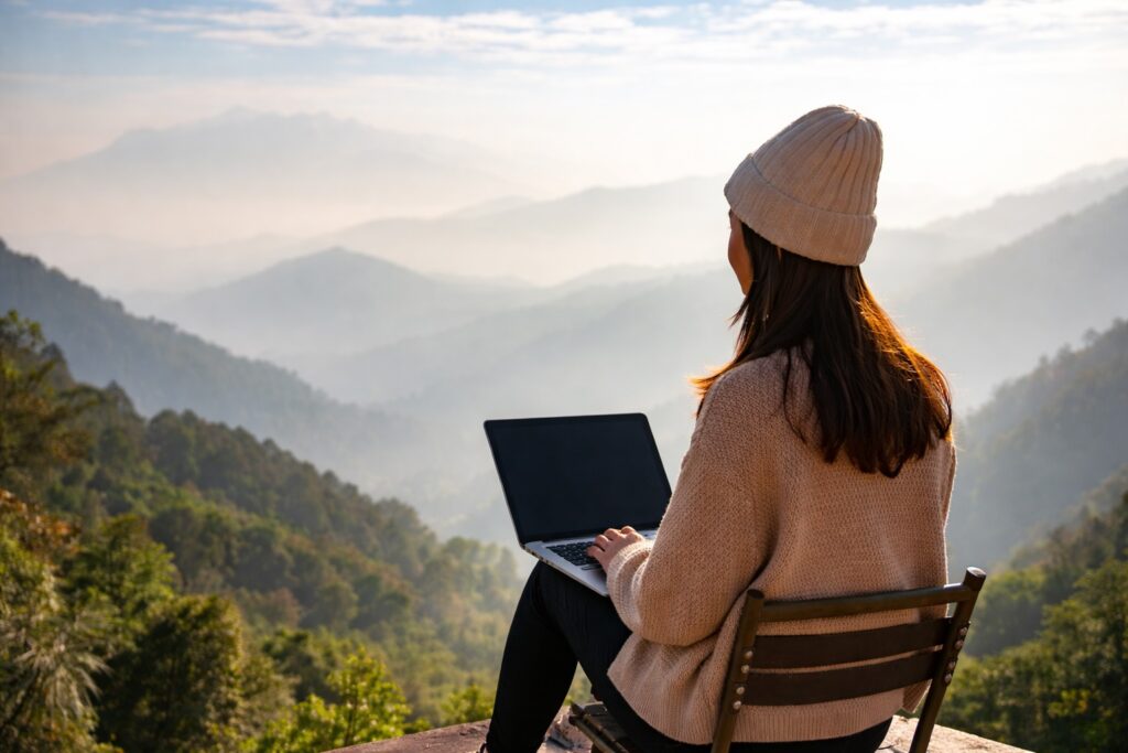 A remote worker using a laptop with a blurred foreground view in the mountains, representing internet and power in Dharamshala for remote work