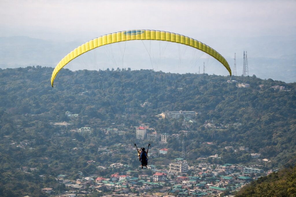 Paragliding over Dharamshala with aerial view of Kangra valley and hillside town below