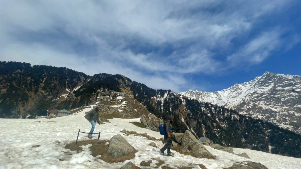 Solo female traveller trekking through snow-covered mountains in Dharamshala with Himalayan views
