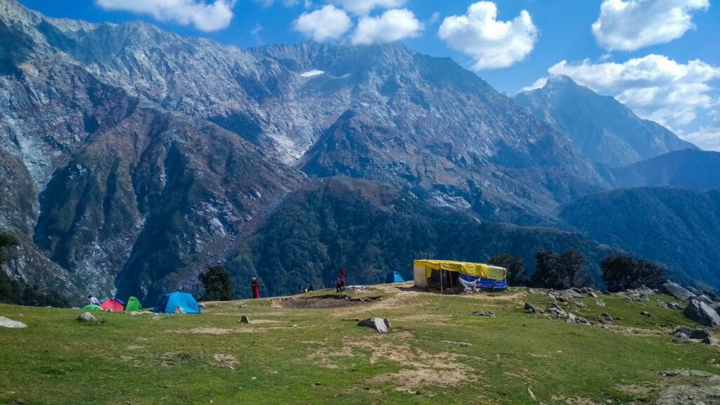 Triund Trek Dharamshala campsite with tents and Dhauladhar mountain views at the top