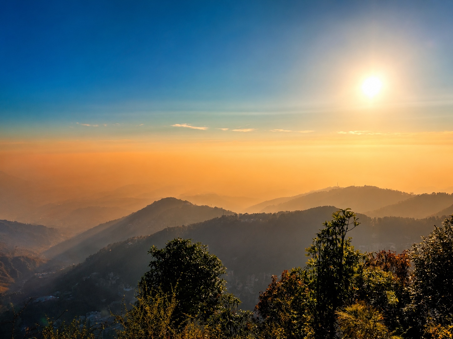 Dharamshala in June with layered mountain views, clear skies, and warm summer sunshine