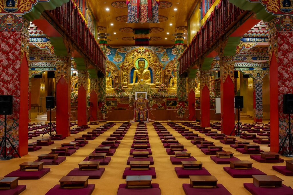 Interior prayer hall of Sherabling Monastery with Buddha statue, meditation cushions, and Tibetan artwork