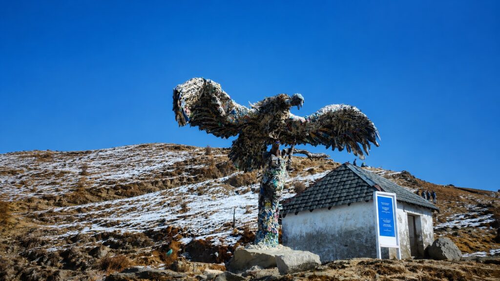 Bir Billing paragliding takeoff area featuring a large eagle sculpture made from recycled materials with the Himalayan landscape in the background.